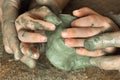 Hands of adult helping child to work with blue clay