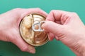 The hands of an adult open food for cats and dogs, on a green background. Top view, copy space. Close-up