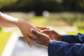 Hands of african american bride and groom placing ring on finger at wedding ceremony in sunny garden