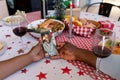 Hands of african american couple on christmas call on smartphone with african american man on screen