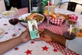 Hands of african american couple on christmas call on smartphone with senior man on screen