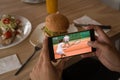 Hands of african american man at restaurant watching tennis match on smartphone