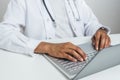 Hands of an afro doctor using a laptop on the top of a white desk