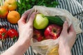 Hands arrange fruits and vegetables from eco bag, promoting sustainability