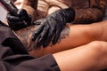 Hands of artist making tattoo of flower design on female thigh Royalty Free Stock Photo