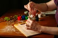 The hands of the artist paint the Easter bunny. Watercolor paints in jars and tubes. Handwork.