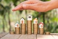 Hands as a protecting roof over a little house. Saving money for house and real estate. Woman hand protecting on  coins and house Royalty Free Stock Photo