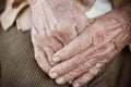 Hands Asian elderly woman grasps her hand on lap, pair of elderly wrinkled hands in prayer sitting alone in his house, World Kind