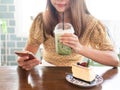 Hands of Asian girl using mobile phone while drinking in cafe. Food and beverage, technology and lifestyle concept. Close up Royalty Free Stock Photo