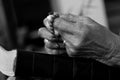 Hands of Asian senior woman holding rosary on bible book in black and white. A spiritual grandmother praying rosary closeup. Royalty Free Stock Photo