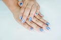 Hands of an Asian woman decorating nails with pearl blue paint