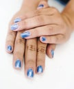 Hands of an Asian woman decorating nails with pearl blue paint