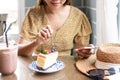 Hands of Asian woman using mobile phone while eating cake in cafe. Food and beverage, technology and lifestyle concept. Close up Royalty Free Stock Photo