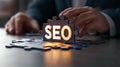 Hands assembling a puzzle piece with SEO letters on a desk
