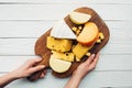 Hands and assorted cheese on wooden board