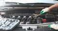 Hands of an auto mechanic with a socket wrench in the engine compartment of a car during repairs Royalty Free Stock Photo