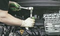 Hands of an auto mechanic with a socket wrench in the engine compartment of a car during repairs Royalty Free Stock Photo