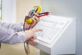 Hands of automation engineer with multimeter on the control panel close-up