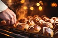 The hands of a baker gently placing hot cross buns into the oven& x27;s cavity