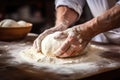 hands of a baker kneading dough on table with flour