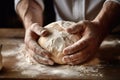 hands of a baker kneading dough on table with flour