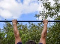 Hands on the bar close-up. The man pulls himself up on the bar. Playing sports in the fresh air. Horizontal bar. Royalty Free Stock Photo