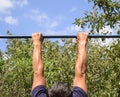 Hands on the bar close-up. The man pulls himself up on the bar. Playing sports in the fresh air. Horizontal bar. Royalty Free Stock Photo