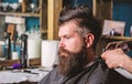 Hands of barber with clipper and comb, close up. Hipster bearded client getting hairstyle. Barbershop concept. Man with