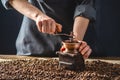 Hands baristas in a dark apron grind on a manual grinder fragrant coffee beans. Selection of fresh coffee for espresso Royalty Free Stock Photo