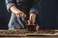 Hands baristas in a dark apron grind on a manual grinder fragrant coffee beans. Selection of fresh coffee for espresso