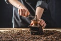 Hands baristas in a dark apron grind on a manual grinder fragrant coffee beans. Selection of fresh coffee for espresso Royalty Free Stock Photo