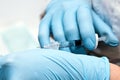 Hands of the beautician in blue gloves holding syringe. The cosmetologist prepares for a injection cosmetology procedure Royalty Free Stock Photo