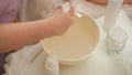Hands of a beautician close up. The process of preparing wet wipes for wiping the skin. Aqueous solution in a white cup. Cosmetic