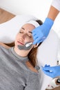 Female hands of a beautician using a cosmetic brush apply a clay mask for peeling on the face of a young woman Royalty Free Stock Photo