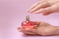 Hands with beautiful manicure holding a red perfume bottle Royalty Free Stock Photo