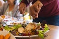 Hands of biracial senior man cutting meal at christmas dinner in sunny dining room