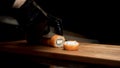 Hands in black gloves cut Philadelphia roll with sharp knife on wooden board, on black background. Salmon and Royalty Free Stock Photo