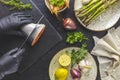 Hands in black gloves cut trout fish on black stone cutting board surrounded herbs, onion, garlic, asparagus, shrimp, prawn in Royalty Free Stock Photo