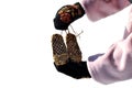 Hands with black mittens with russian traditional pattern holding bast shoes  on white background Royalty Free Stock Photo