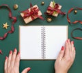 Hands with Blank open notepad on a green background near Christmas presents, mockup Royalty Free Stock Photo