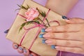 Hands with blue artificial french manicured nails holding a gift box