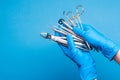 Hands in blue gloves holding dental equipment and metal instruments