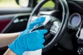 Hands with blue gloves then sprinkling disinfectant and cleaning the car