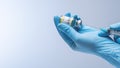 Hands in blue latex gloves fill in syringe with vaccine from glass vial.