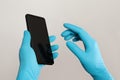 Hands in blue medical gloves holding smartphone on white background Royalty Free Stock Photo
