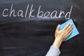 Hands with a blue rag are erasing the blackboard with the inscription chalk Board