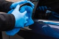 Hands in blue rubber gloves with a blue microfiber rag rub and polish the car mirror. Wash the car yourself Royalty Free Stock Photo