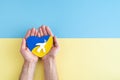 Hands on blue and yellow background holding heart with Ukrainian flag colors with white dove and olive branch Royalty Free Stock Photo