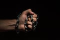 Hands bound in metal chains on a black background