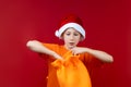 In the hands of a boy who is wearing a Santa Claus hat, a yellow gift bag that he wants to open Royalty Free Stock Photo